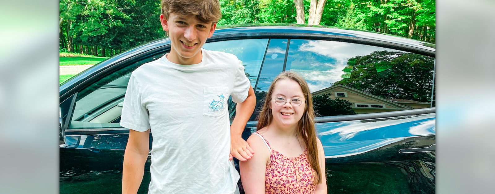 William and Penny stand together in front of a car.