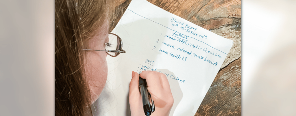 photo of Penny looking down at a wooden table and writing a list on a piece of paper