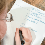 photo of Penny looking down at a wooden table and writing a list on a piece of paper
