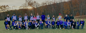 photo of a soccer team posing in front of fall trees with the sun setting behind them