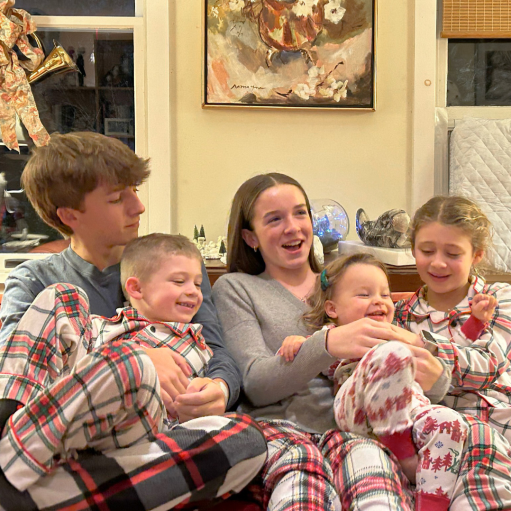 cousins wearing Christmas pjs and sitting on a couch
