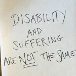 a large piece of white paper is on a wooden floor with the following written in large, all caps letters: “Disability and suffering are not the same."