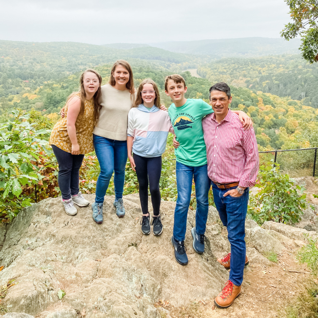 Becker family stands on a rocky outcropping with an autumn forest far below