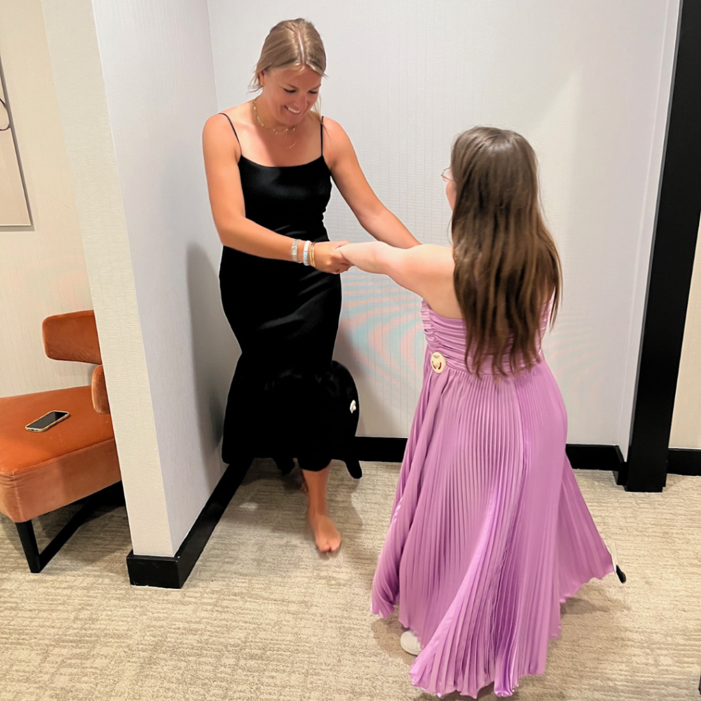 a friend and Penny try on prom dresses and dance in the changing room