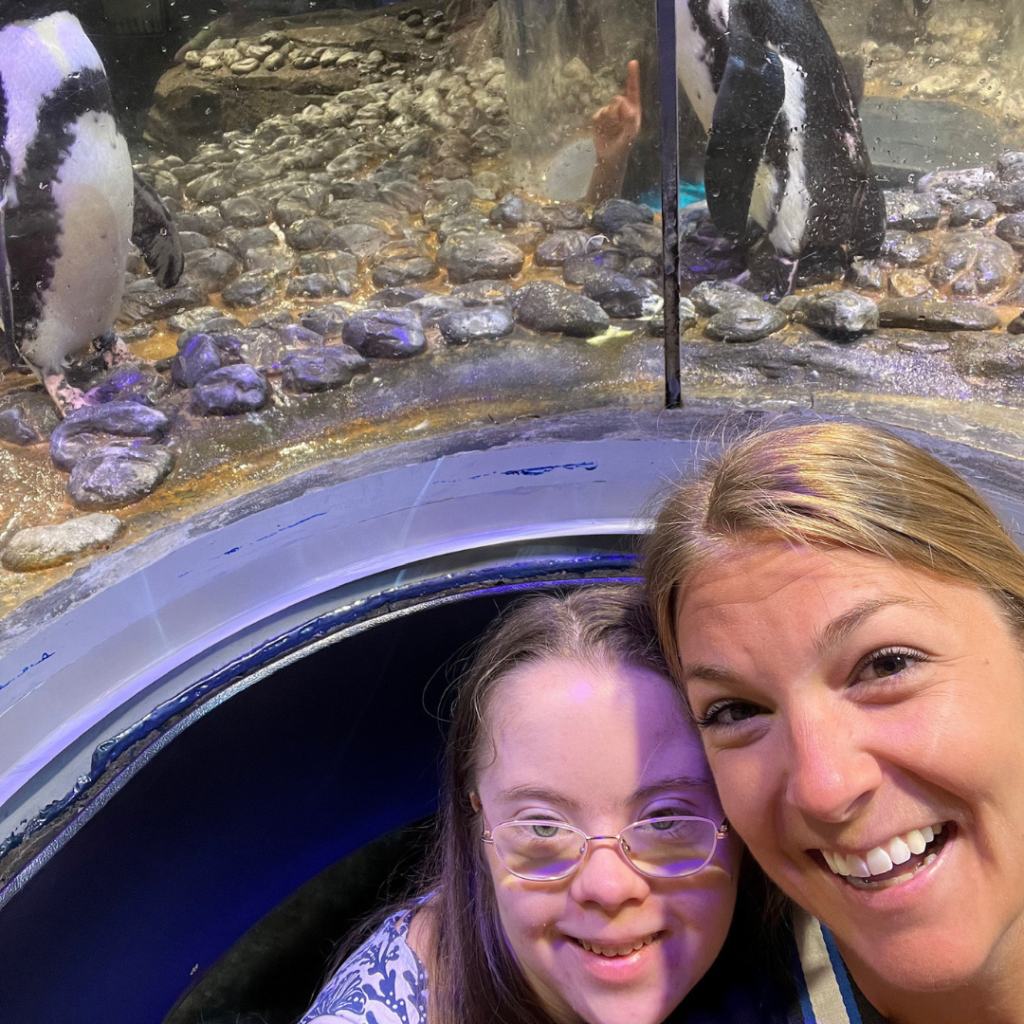 Penny and her Hope Heals camp friend, Caroline Young, take a selfie in front of a penguin exhibit