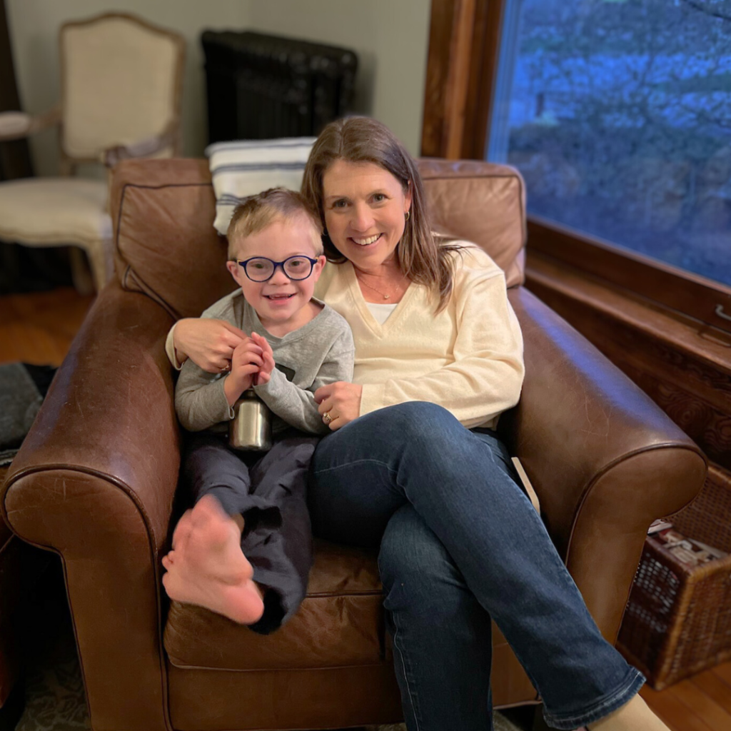 photo of Amy Julia sitting in a chair with a little boy who has Down syndrome