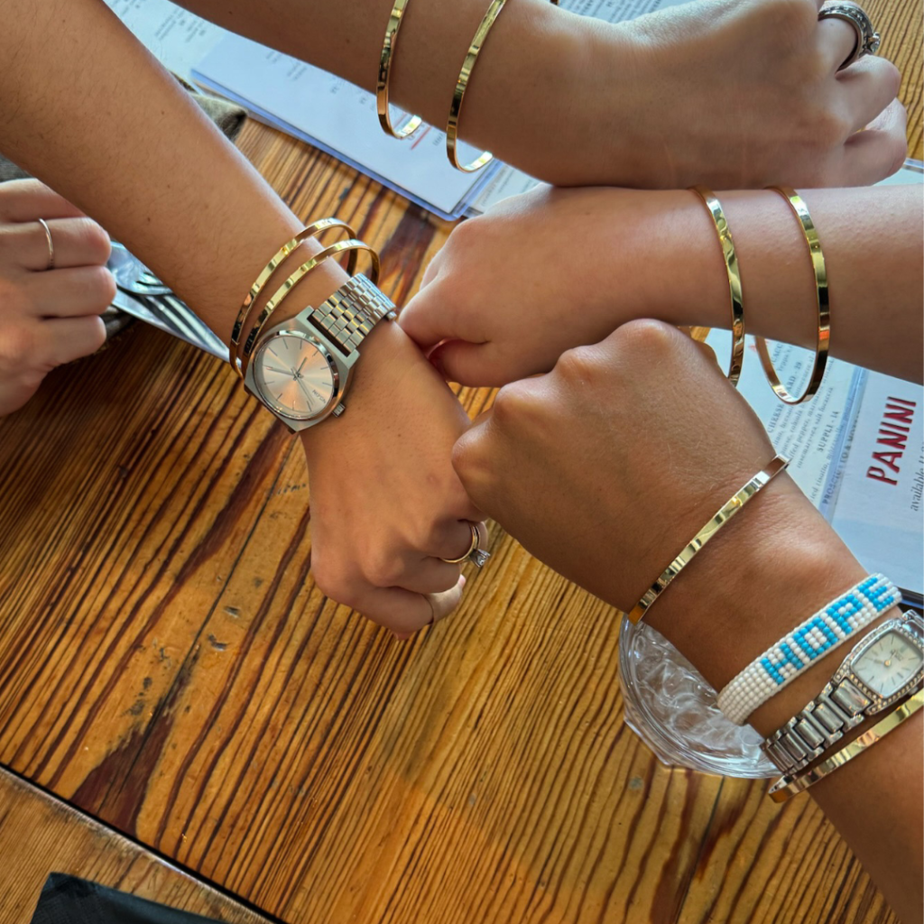 gold friendship bracelets on the arms for four women