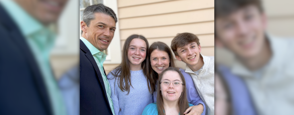 candid photo of Amy Julia's family grouped together smiling for a selfie outside in front of a house