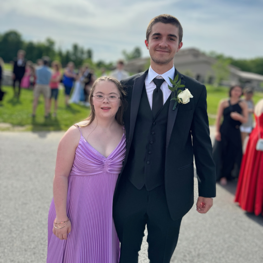 an outdoor photo of Penny wearing a purple prom dress and posing with a friend