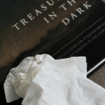 wadded up tissues on top of the Treasures in the Darkness book