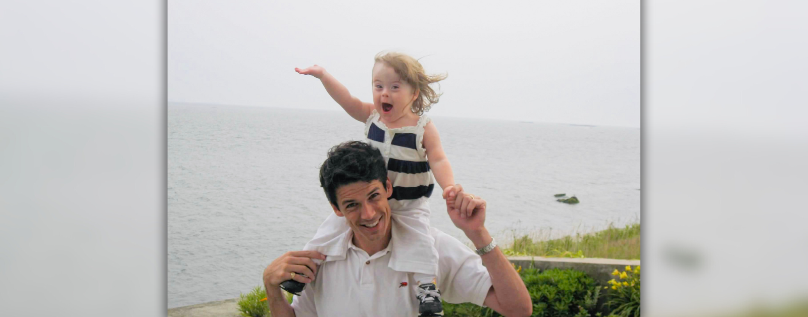 photo from 2008 of Peter holding two-year-old Penny on his shoulders with the ocean in the background]