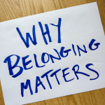 a piece of white paper on a wooden table with the words written in marker: Why Belonging Matters