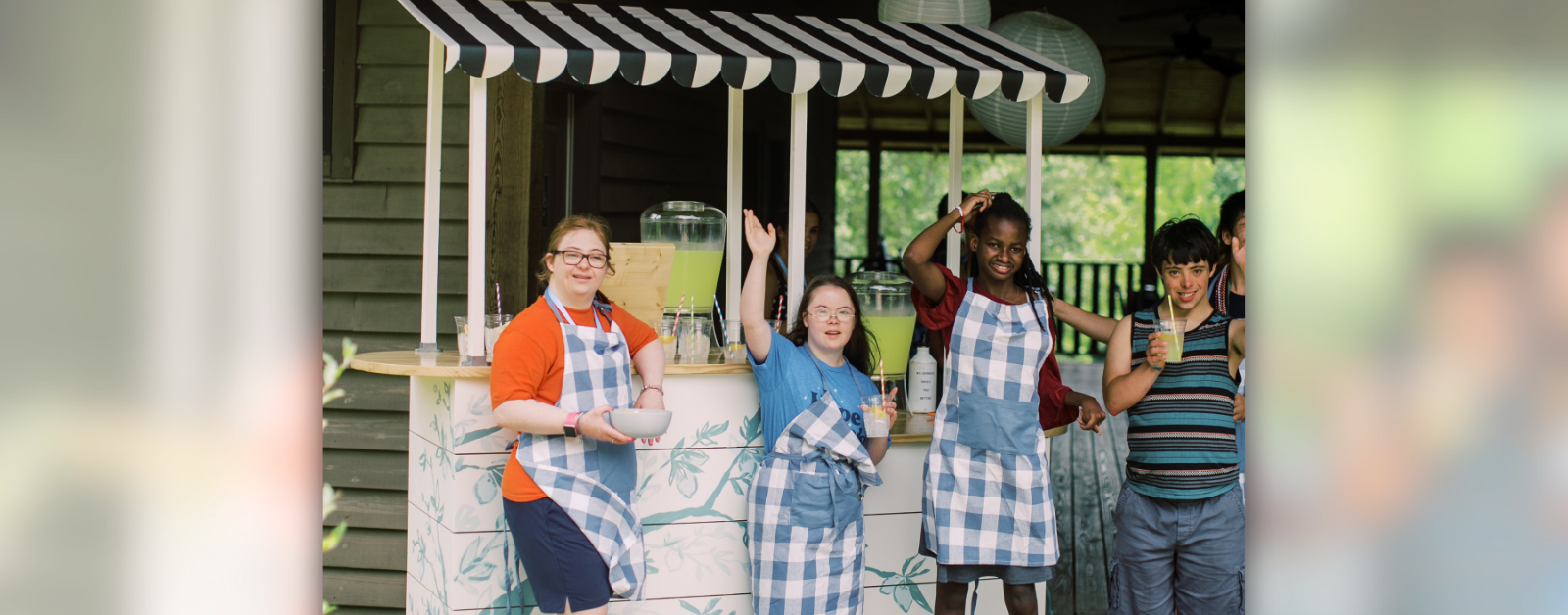 photo of Penny and other teens with disabilities standing in front of a lemonade stand and waving