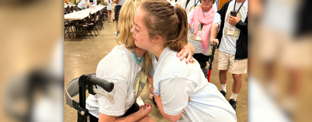 Katherine Wolf and Penny give each other a hug. They are both wearing Hope Heals Camp t-shirts