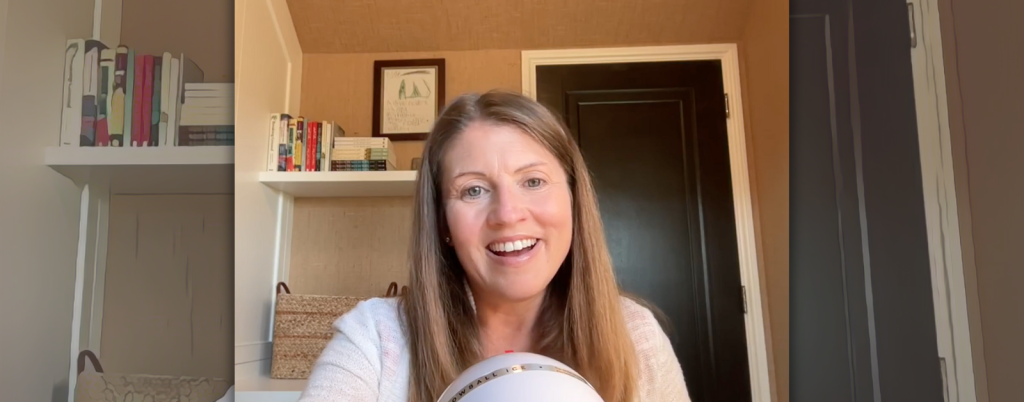 screenshot of Amy Julia recording a podcast. She is sitting in her office with a mic in front of her. She is smiling widely!