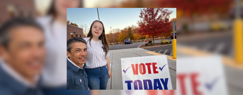 Peter and Penny take a selfie outside by a Vote Today sign