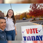 Peter and Penny take a selfie outside by a Vote Today sign