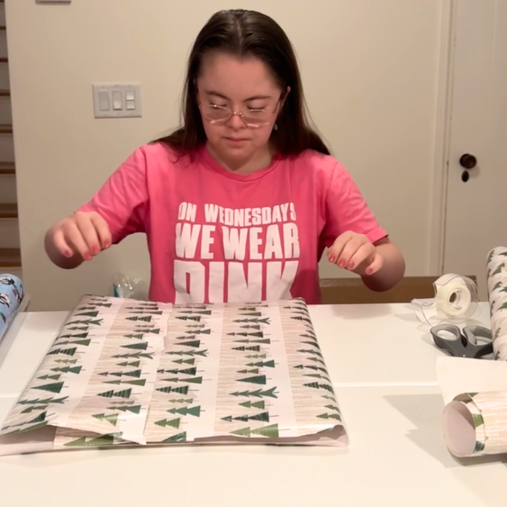 Penny taping Christmas wrapping paper around a gift