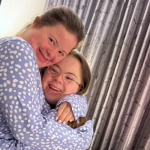 Rachel and Penny are wearing matching blue pajamas with white polka dots are giving each other a hug.