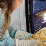 Penny getting muffins out of the oven