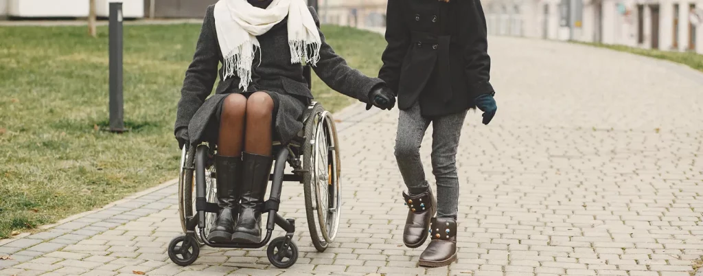 Woman using a Wheelchair Holding Hands with a Girl