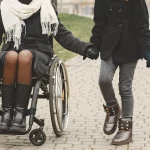 Woman using a Wheelchair Holding Hands with a Girl