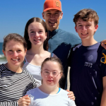 Our family with three teenagers together for spring break on a sandy beach with ocean waves in the background.