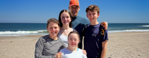 Our family with three teenagers together for spring break on a sandy beach with ocean waves in the background.