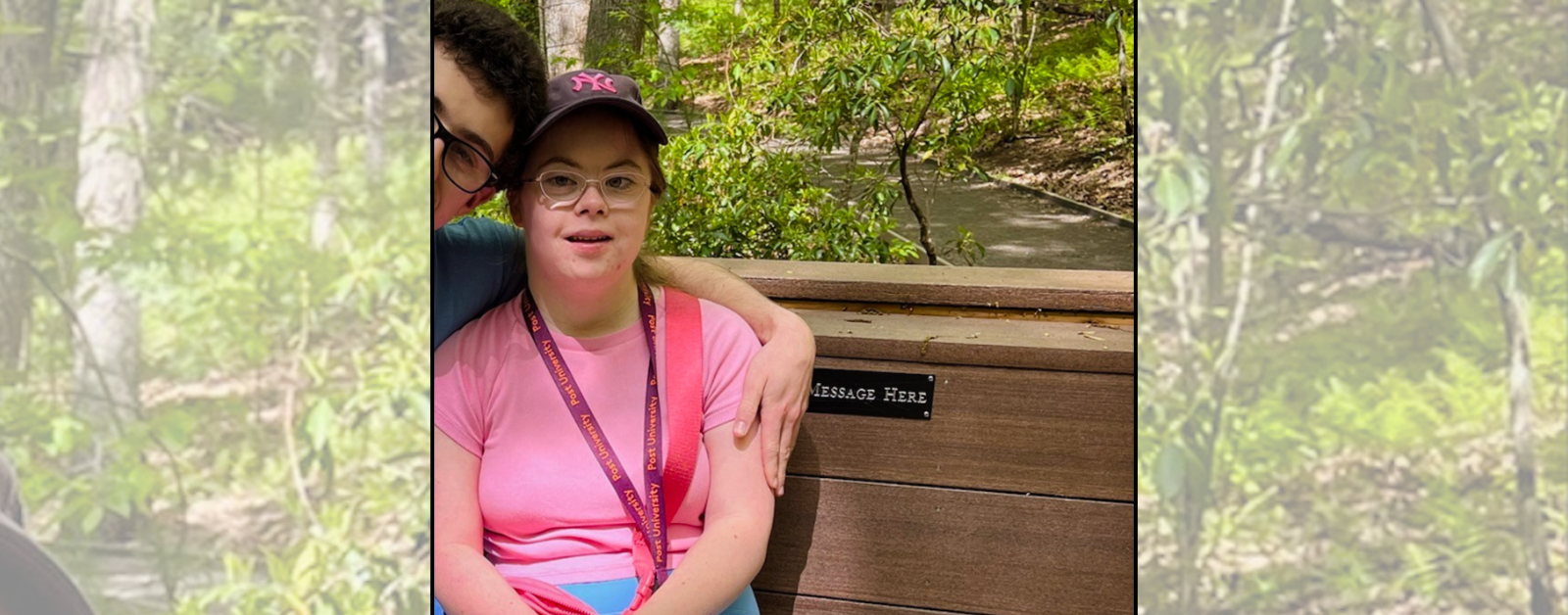Penny sits on a wooden bench in a wooded park. She is smiling. Her boyfriend is sitting next to her, partially out of frame.