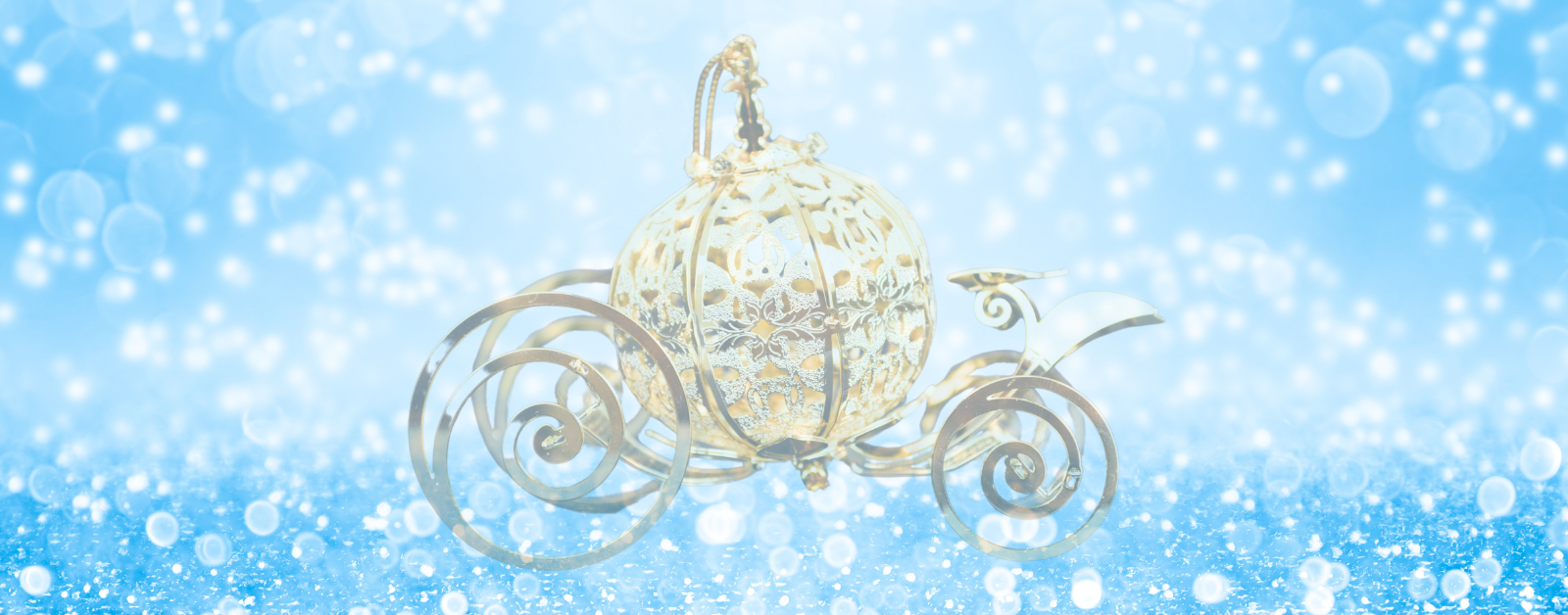 A delicate, ornate gold carriage shaped like a pumpkin sits in the center of a sparkling, snowy blue background. The carriage has intricate scrollwork wheels and a shimmering, fairytale-like appearance, evoking imagery from Cinderella. Soft white lights and bokeh effects surround it, adding a magical, wintery atmosphere.