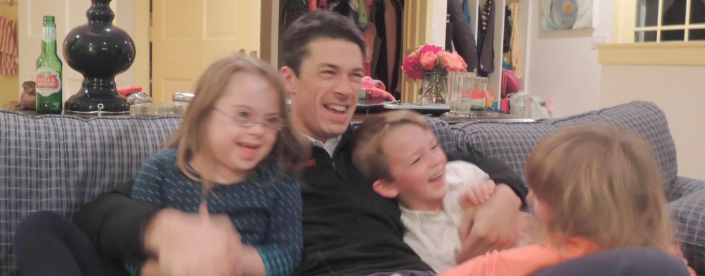 photo from 2013 of Peter and the kids piled together and laughing on the couch