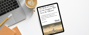 A digital tablet rests on a white desk next to a laptop, coffee with latte art, a yellow pencil, and two notebooks. On the tablet screen is an article from The Atlantic titled “The Work of Caring for My Daughter Will Never Be ‘Efficient’” by Julie Kim. The subtitle reads: “A constellation of people are essential to my disabled child’s life. Trump’s cuts to education and Medicaid threaten to steal them away.” Below the text is an illustration of a person and child sitting on a bench, watching ducks in a pond.