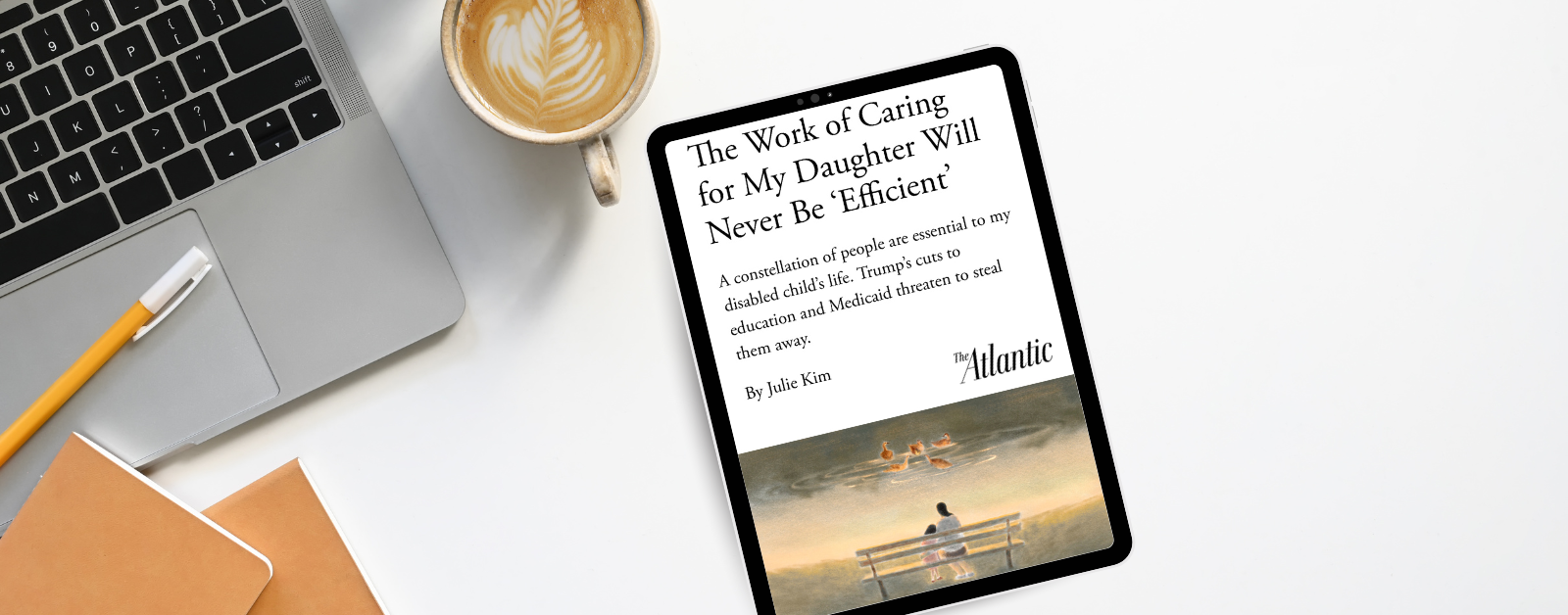 A digital tablet rests on a white desk next to a laptop, coffee with latte art, a yellow pencil, and two notebooks. On the tablet screen is an article from The Atlantic titled “The Work of Caring for My Daughter Will Never Be ‘Efficient’” by Julie Kim. The subtitle reads: “A constellation of people are essential to my disabled child’s life. Trump’s cuts to education and Medicaid threaten to steal them away.” Below the text is an illustration of a person and child sitting on a bench, watching ducks in a pond.