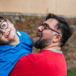 photo of a dad smiling at his disabled son