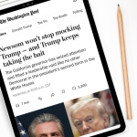 A tablet on a white desk displays a Washington Post article titled “Newsom won’t stop mocking Trump — and Trump keeps taking the bait.” Next to the tablet are a cup of black coffee, a pencil, a white computer mouse, part of a keyboard, and a small potted succulent.