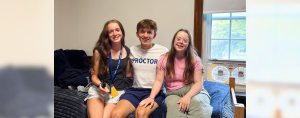 Marilee, William, and Penny sit on a bed in the dorm room at boarding school.