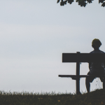 a lonely child sitting on a bench by a tree