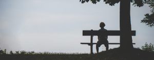 a lonely child sitting on a bench by a tree