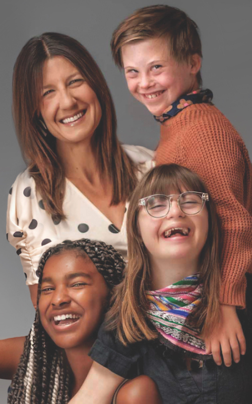 Disability advocate Heather Avis and her kids, two of whom have Down syndrome, pose for a portrait. They are all widely smiling