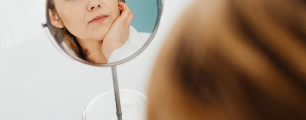 a woman looks into a small mirror