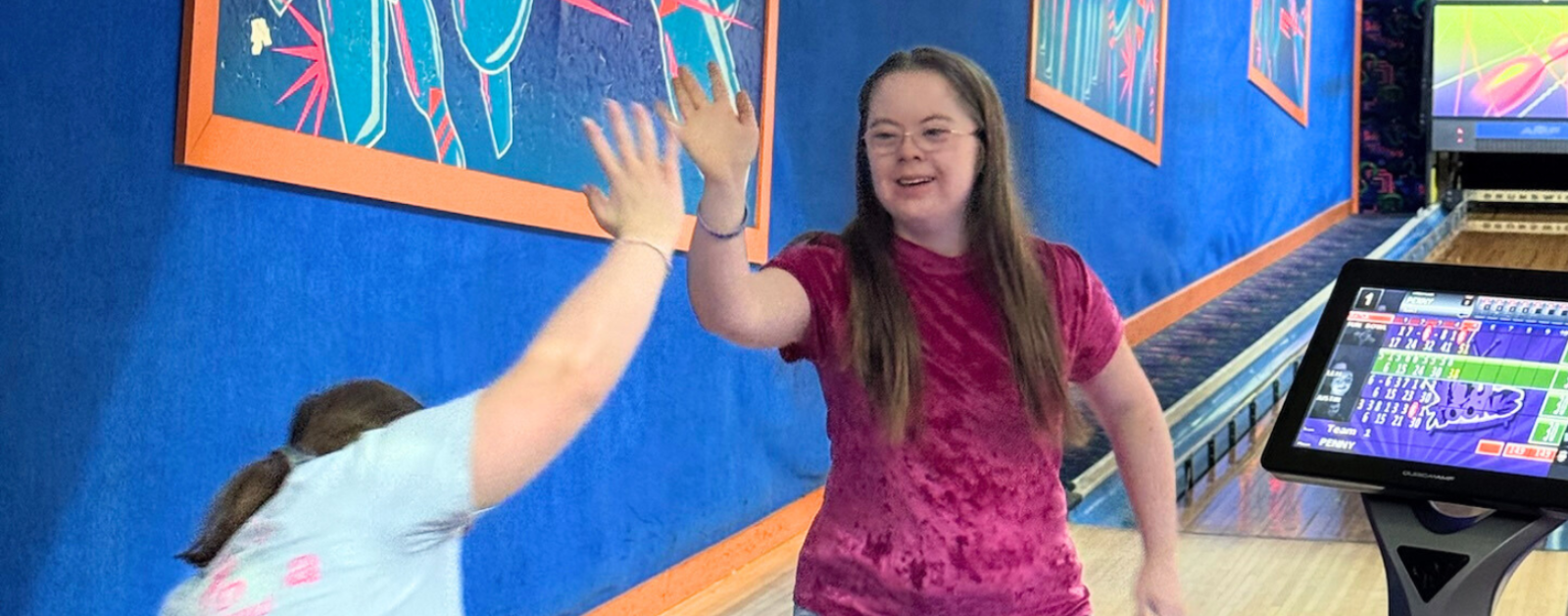 Penny gives her friend a high give at the bowling alley
