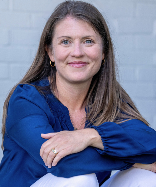 Amy Julia sits on a porch resting her arms on her knees