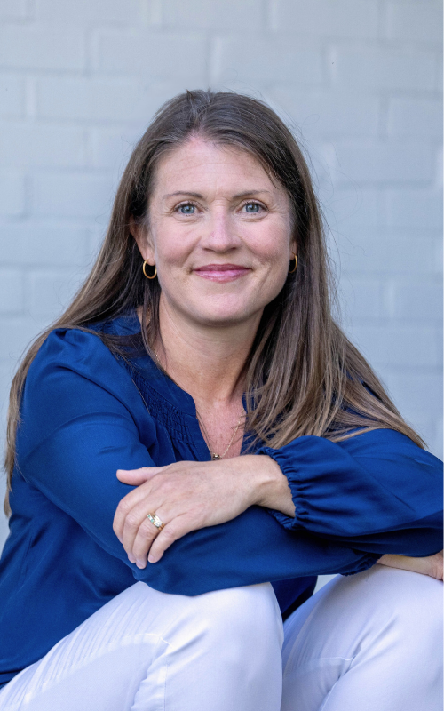 Amy Julia sits on a porch resting her arms on her knees