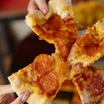 photo of hands pulling pizza slices