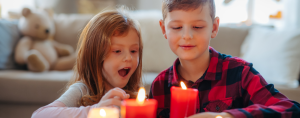 Young girl and boy indoors at home, looking at glowing candles