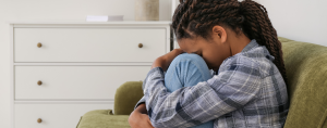 side profile of a child who is sad hiding her face in her knees