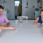 2024 photo by Cloe Poisson of our family sitting around a large white table playing a card game