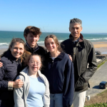 our family posing on a bluff with the ocean in the background in France