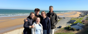 our family posing on a bluff with the ocean in the background in France