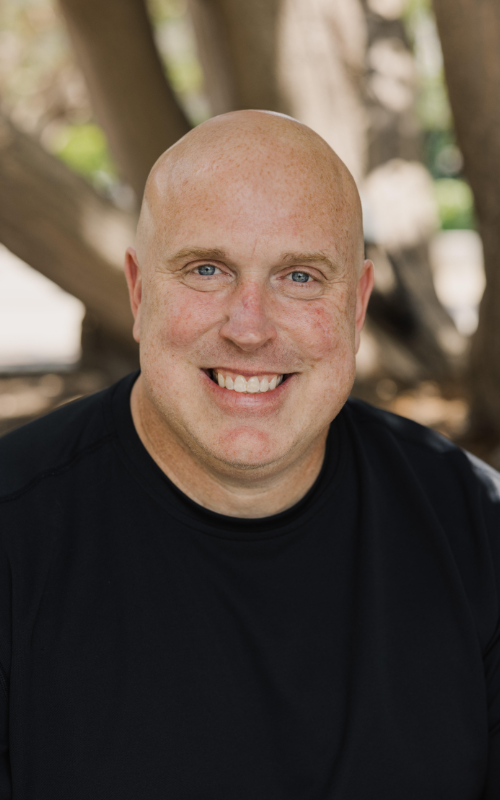 Mike Erre smiles for a portrait outside.